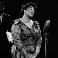 a black and white photo of a woman singing into a microphone