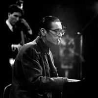 a man in glasses playing a piano