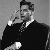 a man in a suit smoking a cigarette