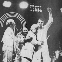 a black and white photo of a group of men on stage